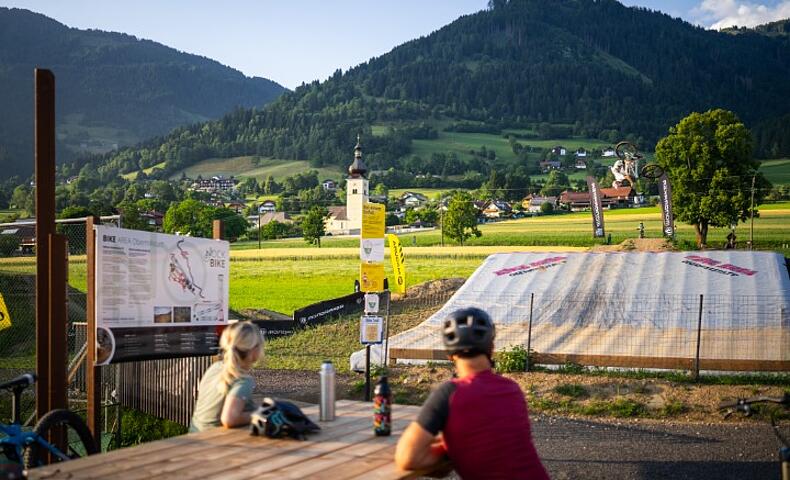 Mountainbiker bei einem Backflip-Sprung in den Bagjump Airbag in der Bike Area Obermillstatt vor Bergpanorama
