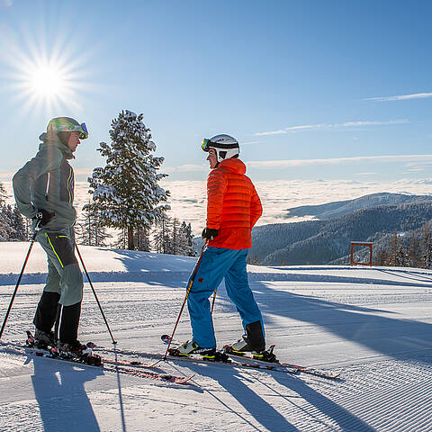 2 Skifahrer stehen auf der Piste im Sonnenschein