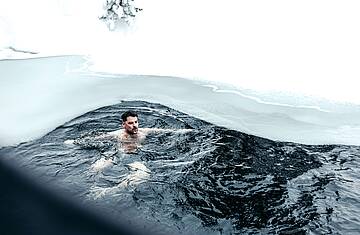 Mann schwimmt im teils zugefrorenen Turracher See