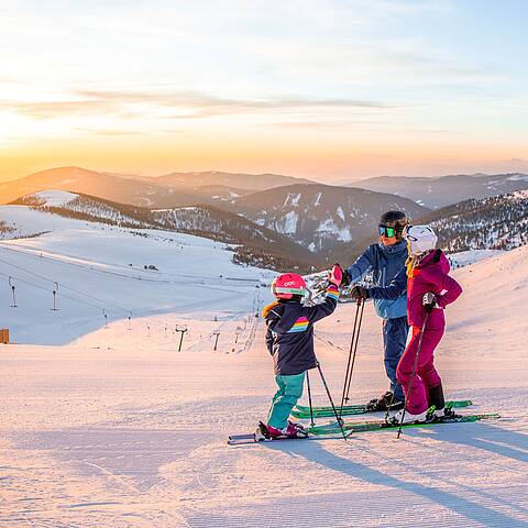 Familie steht mit Ski auf Piste am Falkert