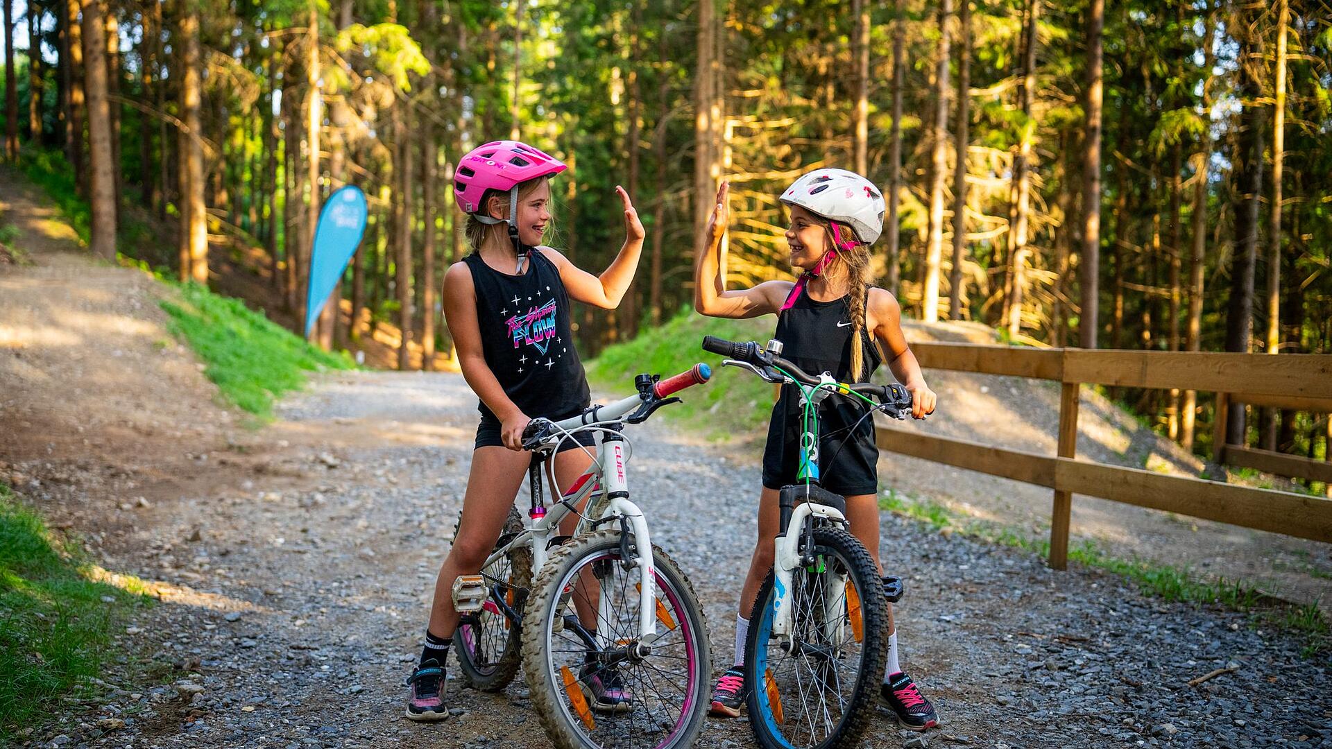 Zwei Mädchen stehen mit ihren Mountainbikes in der Bike Area und klatschen sich ab