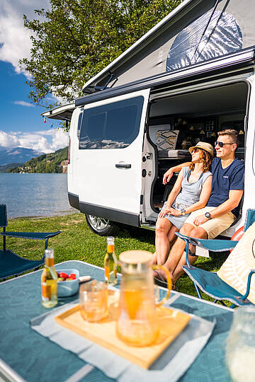 Pärchen genießt Frühstück im Campingbus am See