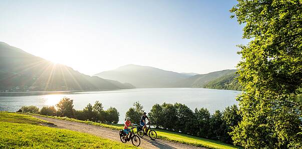 Mann und Frau fahren mit ihren Fahrrädern den Radweg am Millstätter See entlang