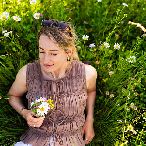 Frau sitzt im Gras und genießt die Natur