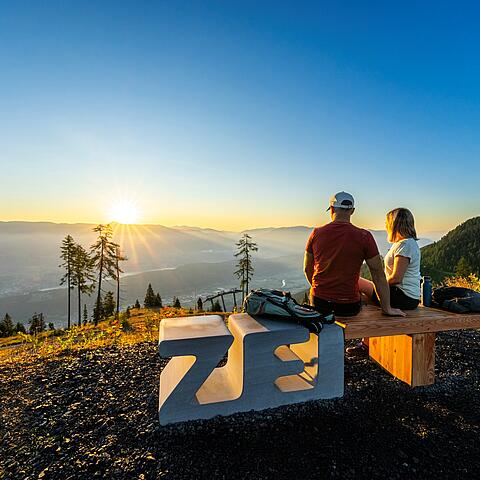 Pärchen sitzt auf Zeitbank am Goldeck und genießt den Ausblick