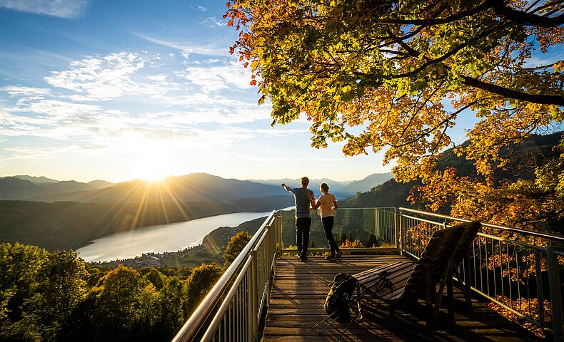 Pärchen steht am Sternenbalkon im Herbst mit Blick auf den Millstätter See