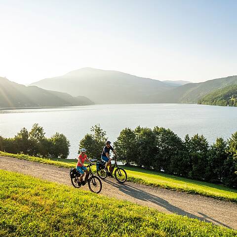 2 Personen fahren mit ihren Rädern den Radweg um den Millstätter See entlang