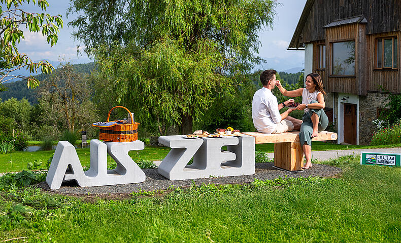 Pärchen sitzt auf der Zeitbank und genießt das gemeinsame Picknick