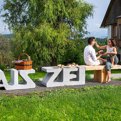 Pärchen sitzt auf der Zeitbank und genießt das gemeinsame Picknick